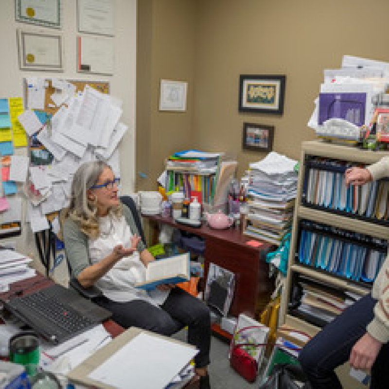 A professor chatting with a graduate student during office hours