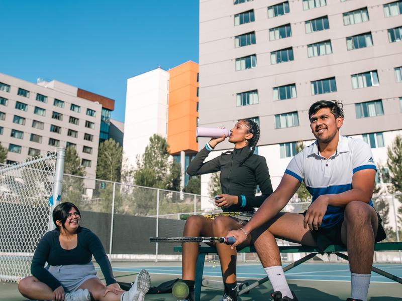 Students sitting in tennis court