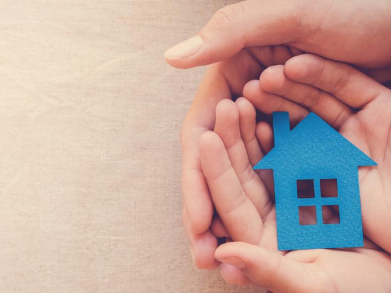 Human hands holding a blue icon of a house