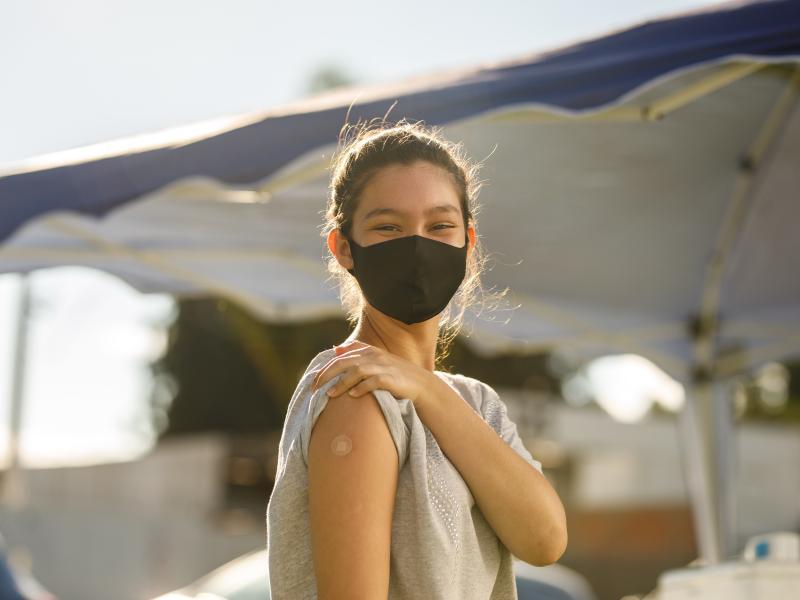 Student with mask showing arm with bandaid