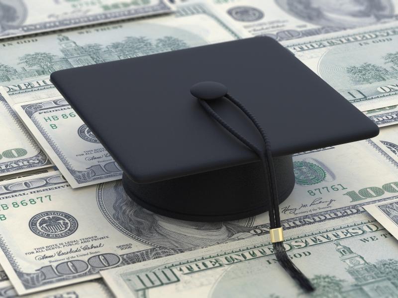Graduation cap sitting on top of money. 