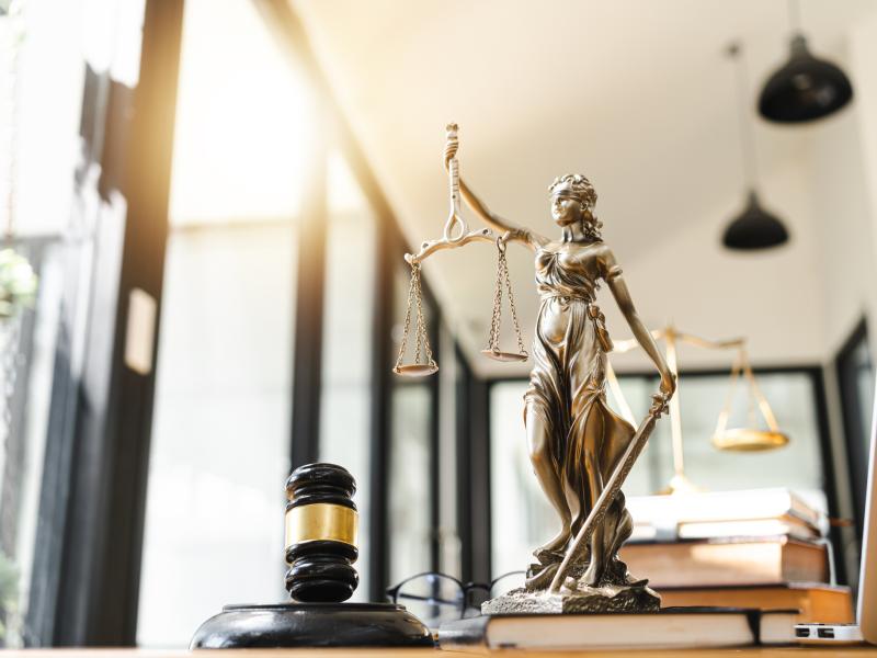 Gavel and statue holding scales referencing the justice system. 