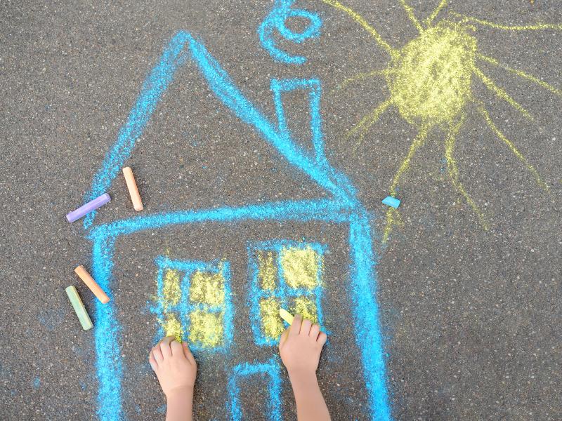Child chalk drawing of a blue and yellow house and sun
