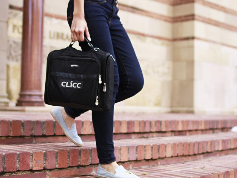 Person walking out of Powell Library holding a bag with the CLICC logo
