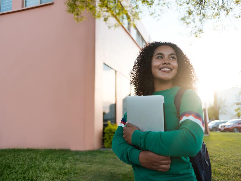 Student holding books and smiling